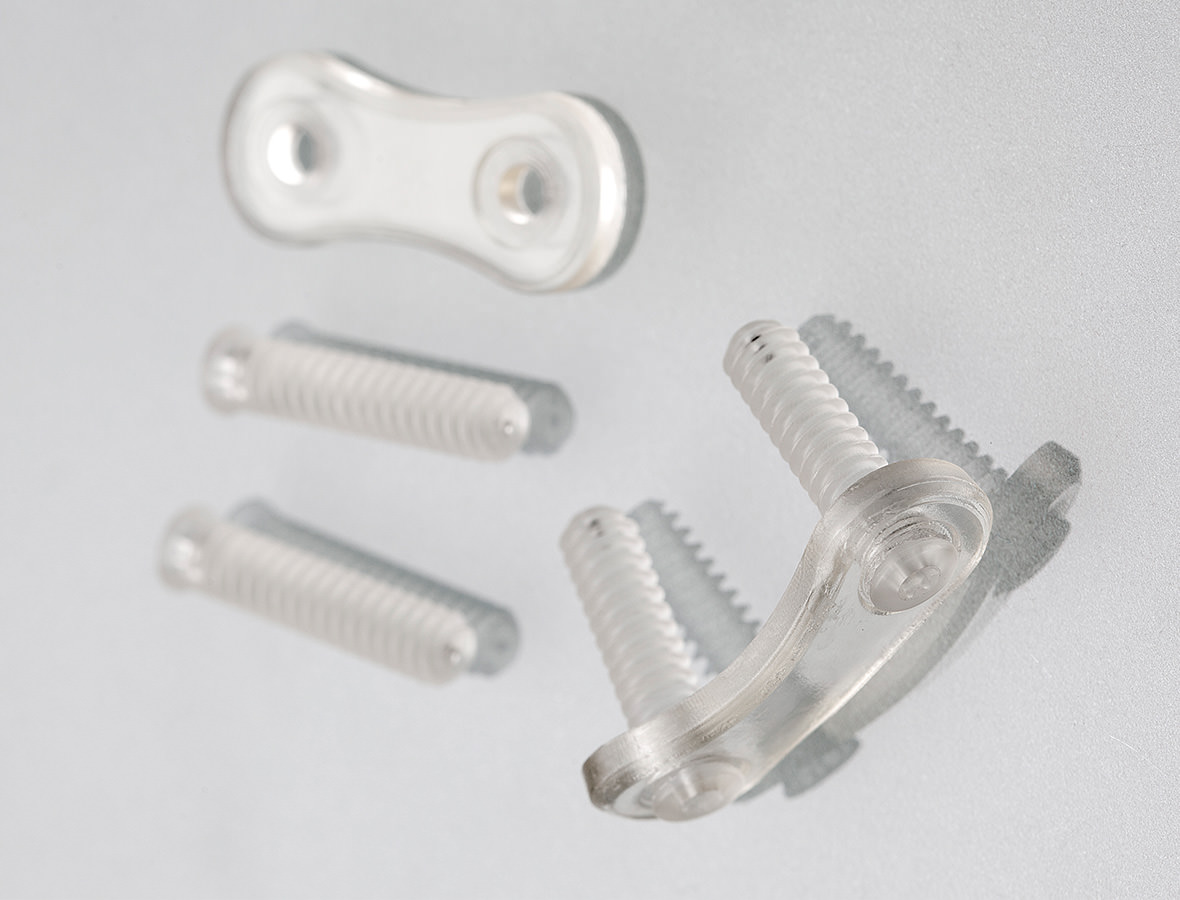 Surgical plates and screws on a grey surface.