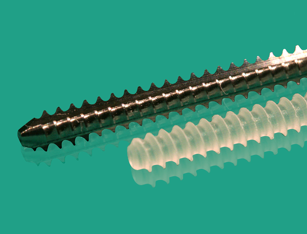 A resorbable screw next to a metal screw against a green background